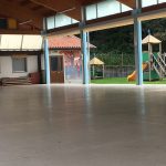 Area coperta con pavimentazione che si affaccia su un'area giochi esterna