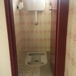 Cabina wc stretta con toilette alla turca a pavimento e cassetta di scarico sospesa