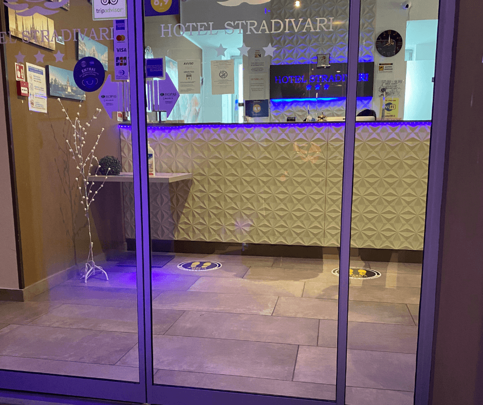 Ingresso a vetri della reception dell'Hotel Stradivari, illuminata con luci blu e viola