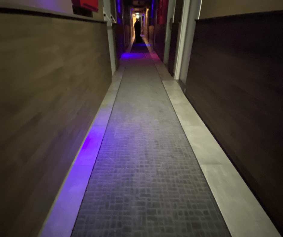 Corridoio stretto e buio di un hotel con una striscia di moquette rialzata al centro del pavimento