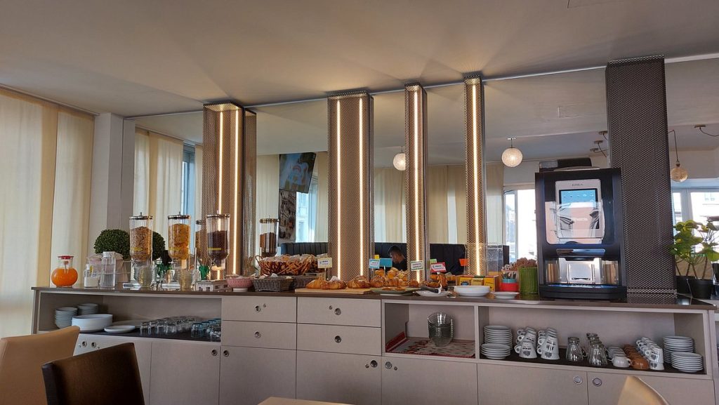 Buffet della colazione di un hotel con dispenser di cereali, pasticceria e macchina del caffè